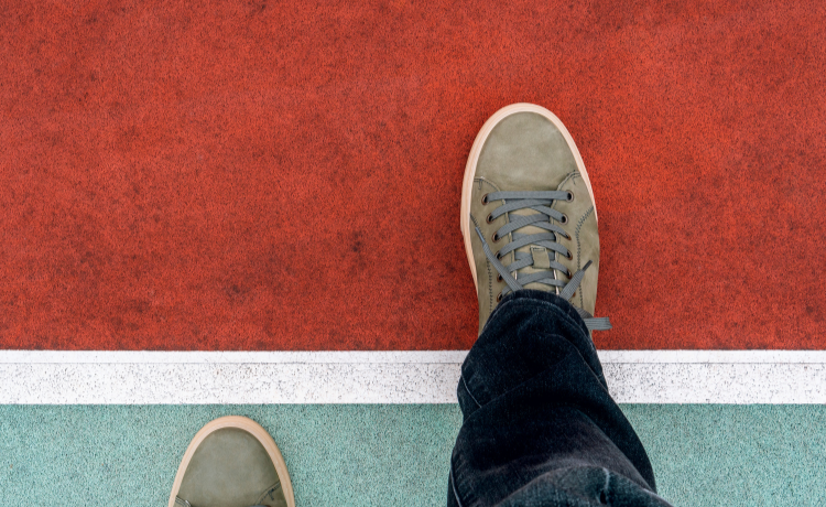 Person standing on blue ground stepping over a white line into red ground