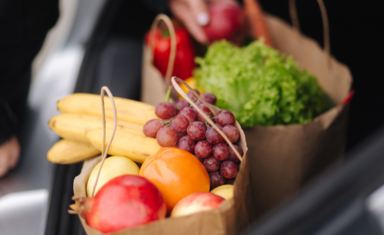 Two brown paper bags holding fruits and vegetables